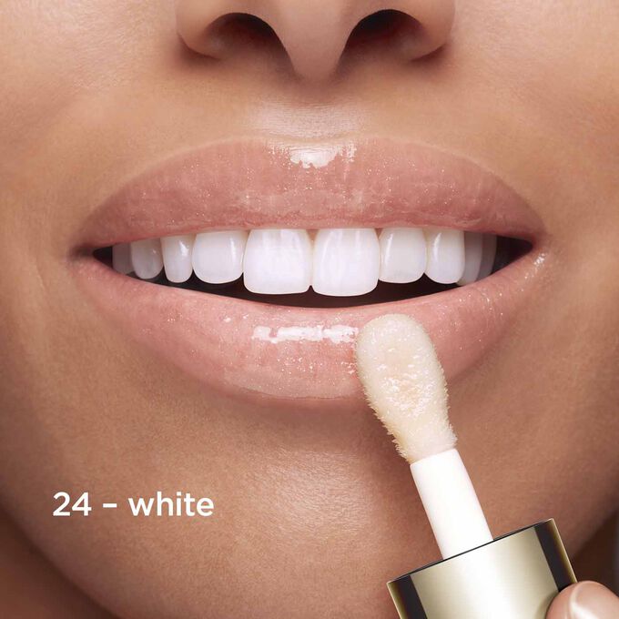 Close-up of smiling lips to showcase the texture and colour of the white lip oil shade on her skin tone